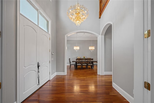 foyer entrance with dark wood-type flooring, a high ceiling, and a notable chandelier