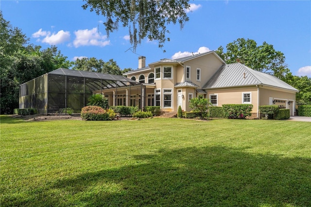 rear view of house with glass enclosure, a garage, and a lawn