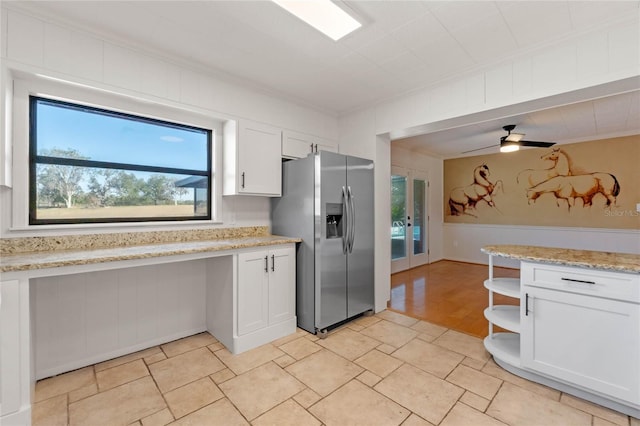 kitchen featuring stainless steel fridge, light stone countertops, and white cabinets