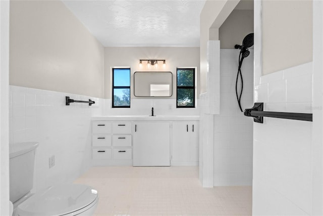 bathroom featuring vanity, tile walls, tile patterned floors, and toilet