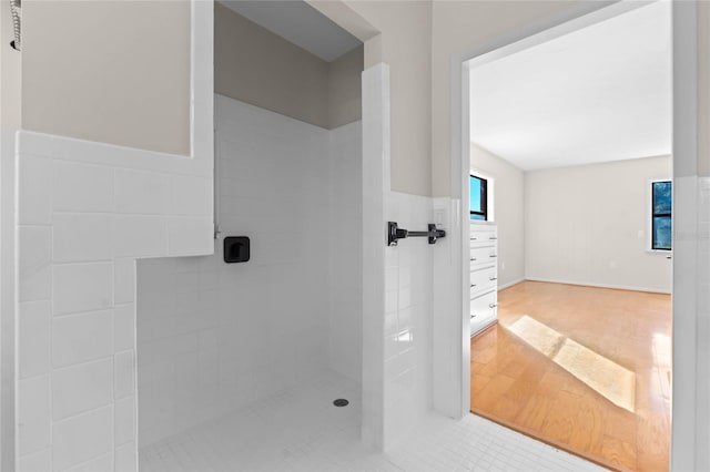 bathroom with a tile shower and hardwood / wood-style flooring