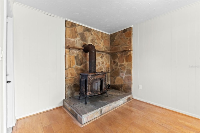 room details with crown molding, hardwood / wood-style floors, and a wood stove