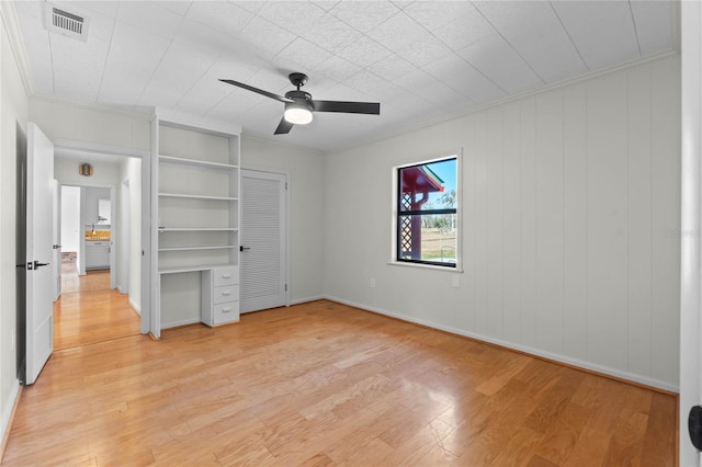 unfurnished bedroom with ceiling fan, ornamental molding, a closet, and light wood-type flooring