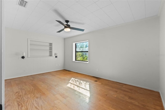 spare room with ceiling fan, ornamental molding, light wood-type flooring, and built in shelves