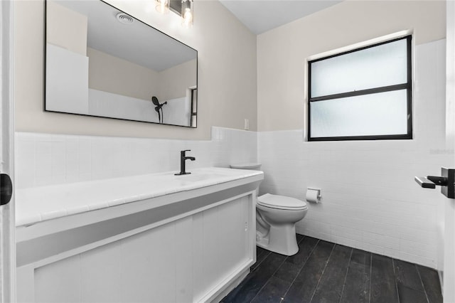 bathroom with hardwood / wood-style flooring, vanity, toilet, and tile walls