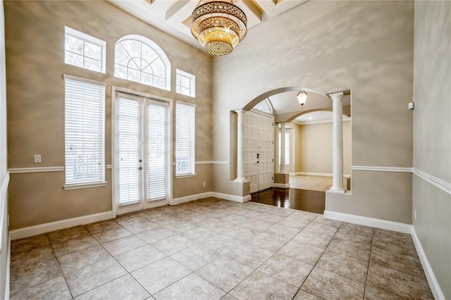 tiled foyer entrance featuring french doors, a towering ceiling, and ornate columns