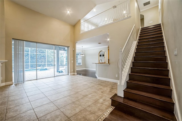 tiled foyer entrance with a high ceiling and ornamental molding