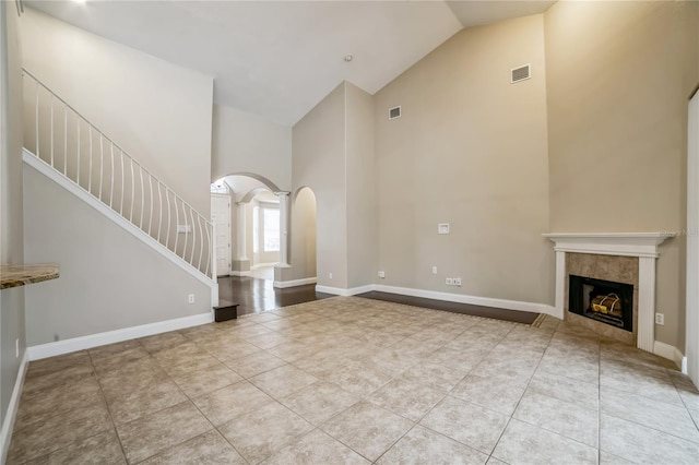 unfurnished living room with high vaulted ceiling, light tile patterned floors, and a fireplace