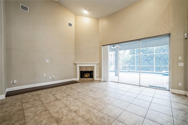 unfurnished living room featuring a fireplace, light tile patterned flooring, and high vaulted ceiling