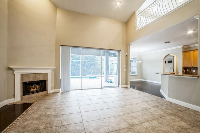 unfurnished living room with a fireplace, sink, light tile patterned floors, and ornamental molding