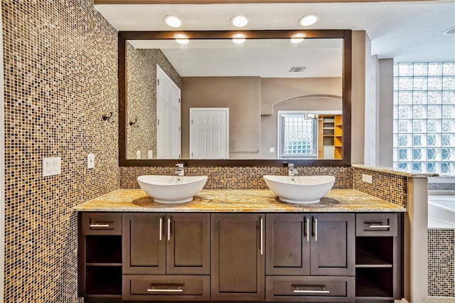 bathroom featuring a washtub, decorative backsplash, and vanity