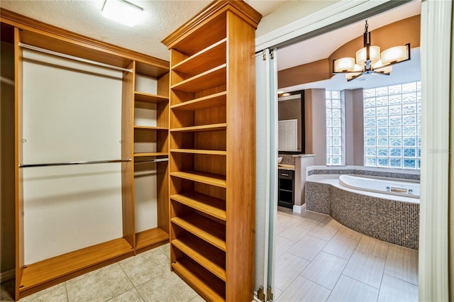 walk in closet featuring light tile patterned floors and a notable chandelier