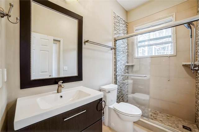 bathroom with a shower with shower door, toilet, and vanity