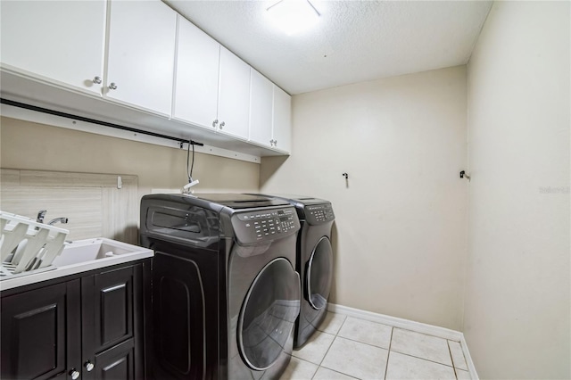 washroom with separate washer and dryer, a textured ceiling, cabinets, sink, and light tile patterned floors