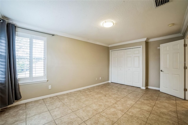 unfurnished bedroom with a closet, crown molding, light tile patterned floors, and a textured ceiling