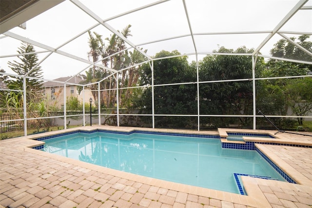 view of pool with a patio, an in ground hot tub, and glass enclosure