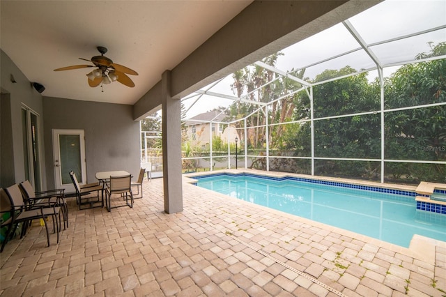 view of swimming pool with glass enclosure, ceiling fan, and a patio