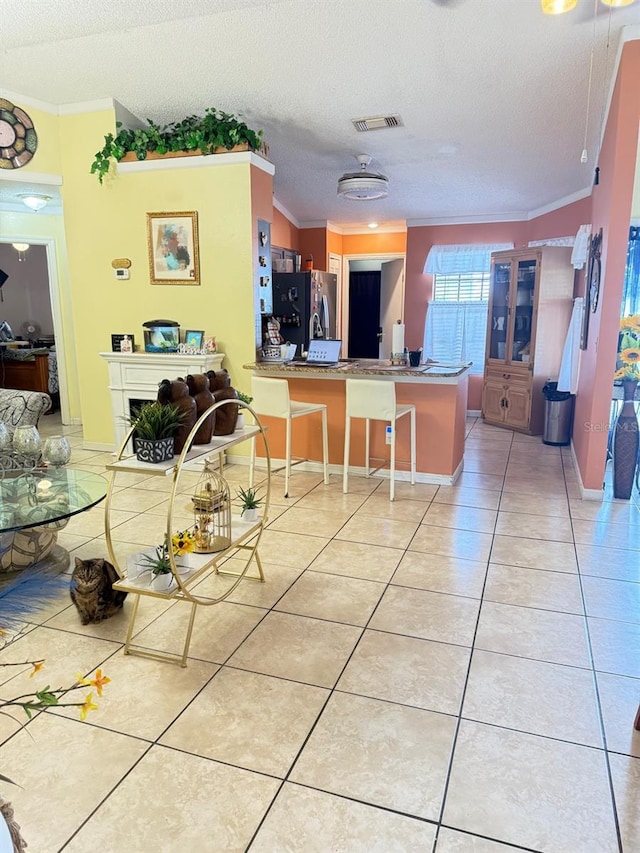 dining space featuring light tile patterned floors, a textured ceiling, visible vents, and crown molding