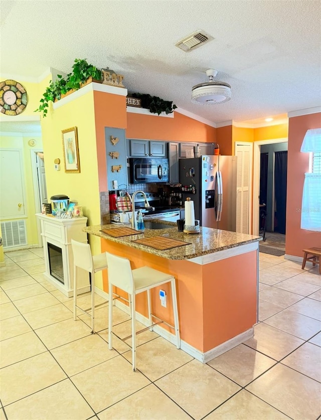 kitchen featuring light tile patterned floors, stainless steel appliances, a breakfast bar, a peninsula, and visible vents