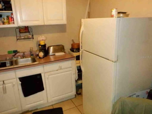 kitchen with open shelves, freestanding refrigerator, white cabinetry, a sink, and light tile patterned flooring