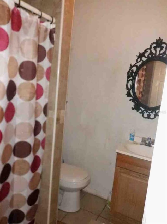 bathroom with a shower with shower curtain, vanity, toilet, and tile patterned floors