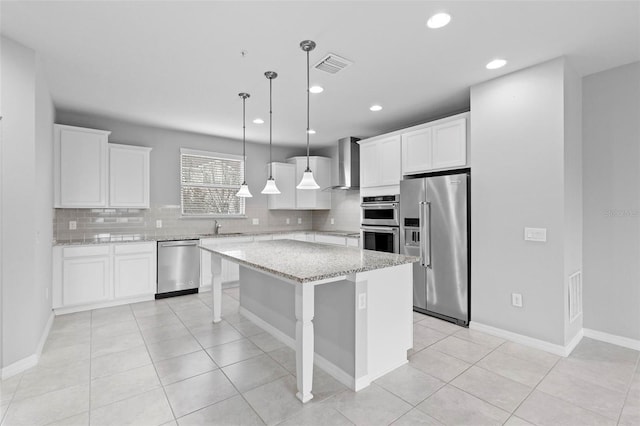 kitchen with tasteful backsplash, a center island, stainless steel appliances, white cabinets, and wall chimney exhaust hood