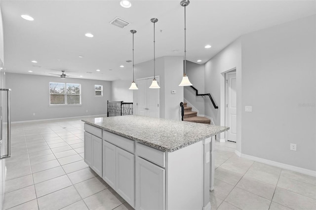 kitchen featuring light stone countertops, pendant lighting, white cabinets, a kitchen island, and ceiling fan