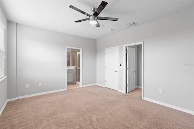 unfurnished bedroom with ensuite bath, light colored carpet, ceiling fan, and a textured ceiling