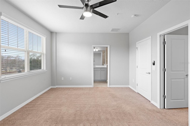 unfurnished bedroom with ceiling fan, light carpet, and connected bathroom