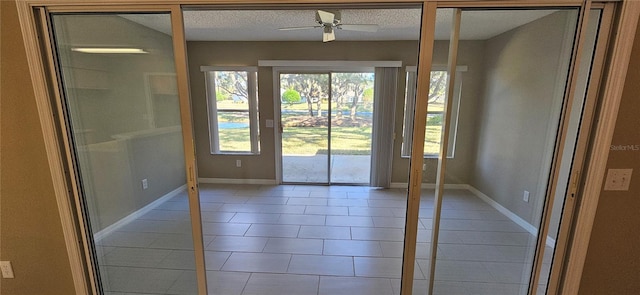 doorway featuring ceiling fan, tile patterned flooring, and a textured ceiling