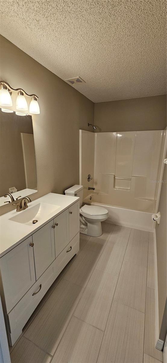 full bathroom with toilet, vanity, bathing tub / shower combination, and a textured ceiling