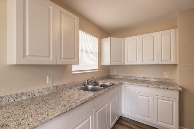 kitchen with white cabinetry, dark wood-type flooring, sink, and light stone counters