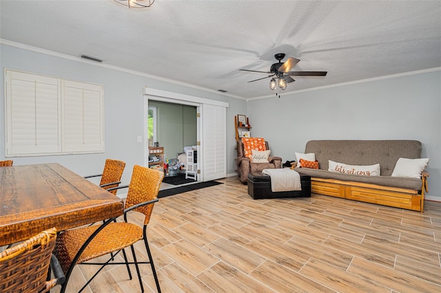 living room with ceiling fan, ornamental molding, and a textured ceiling