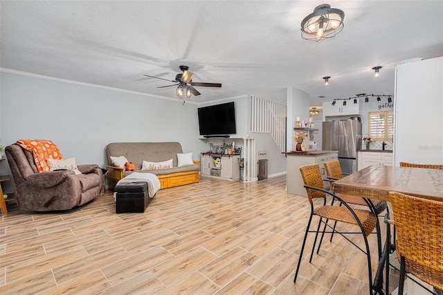 living room with ceiling fan, ornamental molding, and a textured ceiling