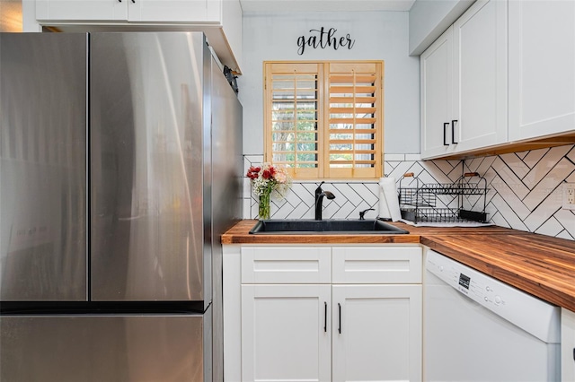 kitchen featuring stainless steel refrigerator, dishwasher, sink, butcher block counters, and white cabinets