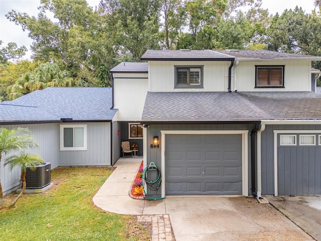 view of property featuring central AC unit, a garage, and a front yard