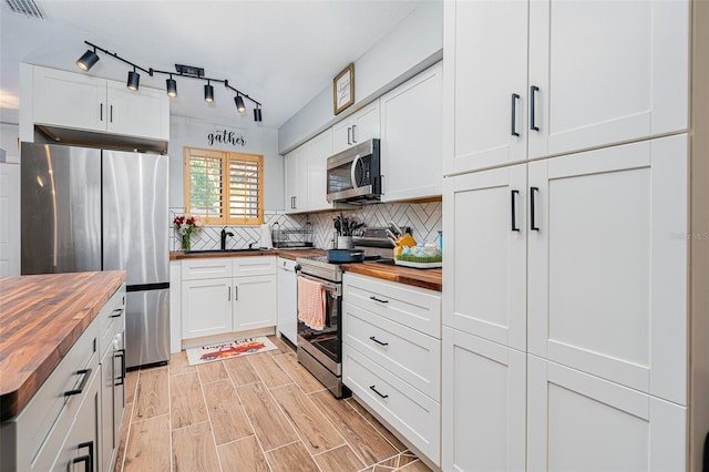 kitchen with white cabinetry, appliances with stainless steel finishes, wooden counters, and decorative backsplash