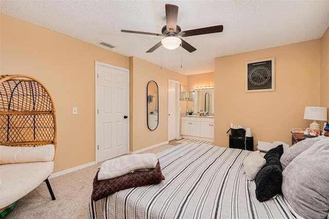 carpeted bedroom featuring ensuite bathroom, a textured ceiling, and ceiling fan