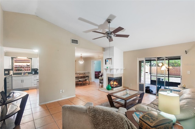 tiled living room with sink, a multi sided fireplace, vaulted ceiling, and ceiling fan