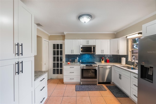 1309 Paradise Ln, Winter Park, FL 32792 - kitchen with appliances with stainless steel finishes, white cabinetry, light tile patterned floors, sink, and backsplash