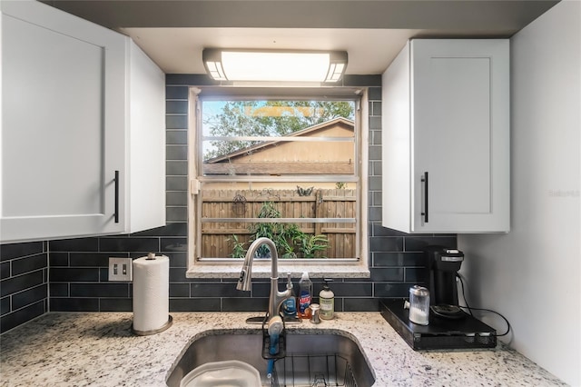 1309 Paradise Ln, Winter Park, FL 32792 - kitchen featuring decorative backsplash, sink, light stone counters, and white cabinets