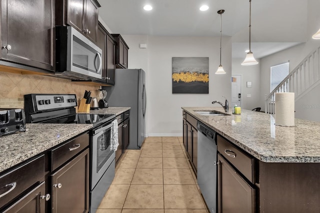 kitchen with pendant lighting, decorative backsplash, sink, an island with sink, and stainless steel appliances