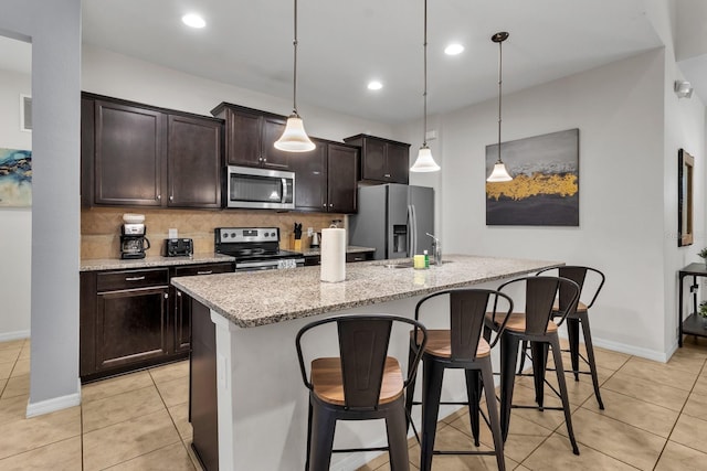 kitchen with stainless steel appliances, hanging light fixtures, and an island with sink