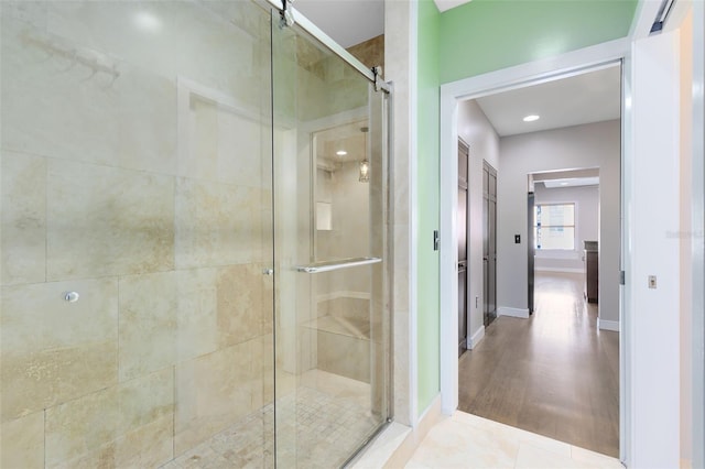 bathroom with a shower with shower door and tile patterned flooring