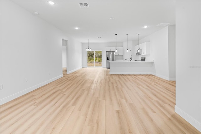 unfurnished living room featuring sink and light hardwood / wood-style floors