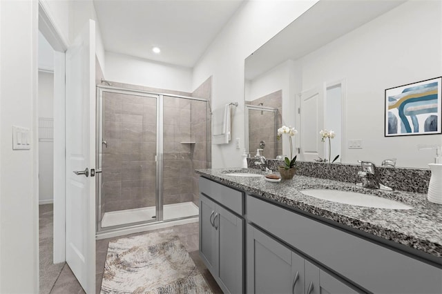 bathroom with a shower with shower door, vanity, and tile patterned flooring