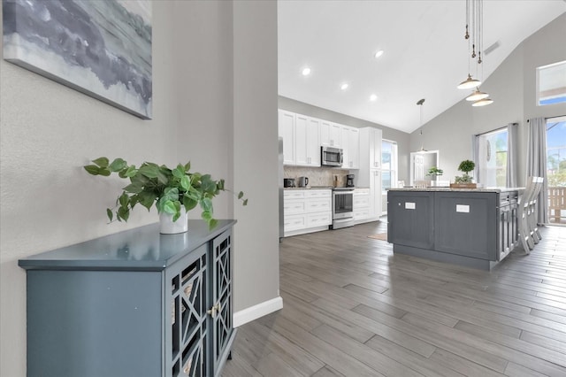 kitchen featuring white cabinets, stainless steel appliances, decorative backsplash, hanging light fixtures, and dark hardwood / wood-style floors