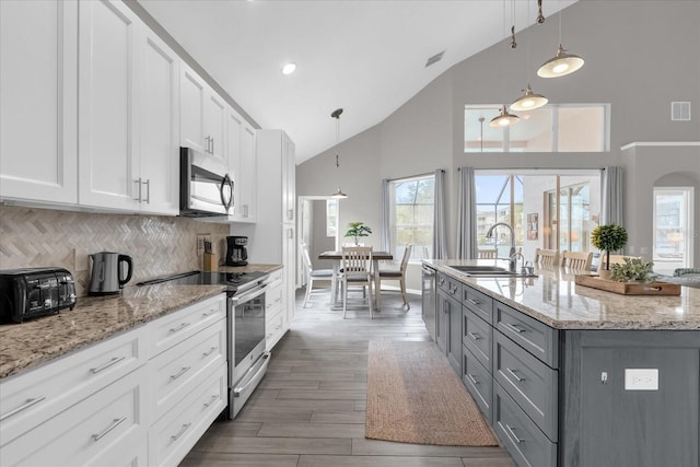 kitchen featuring appliances with stainless steel finishes, backsplash, decorative light fixtures, white cabinets, and sink