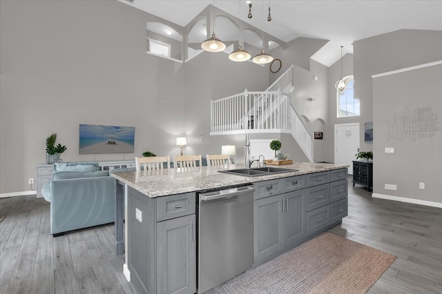 kitchen featuring gray cabinets, pendant lighting, stainless steel dishwasher, a high ceiling, and a kitchen island with sink