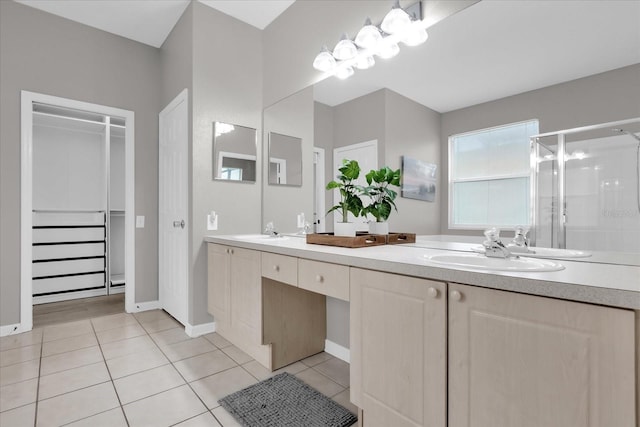 bathroom featuring a shower with shower door, vanity, and tile patterned floors